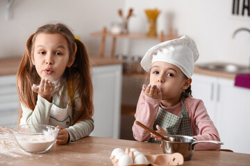 Cute little sisters blowing kiss in kitchen