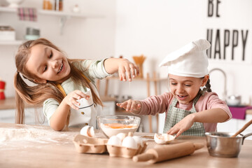 Cute little sisters cooking in kitchen