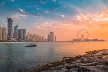 Obraz premium A delightful and colorful sunset over Blue waters Island with the famous Dubai Eye Ferris wheel. Panoramic view of the city in UAE