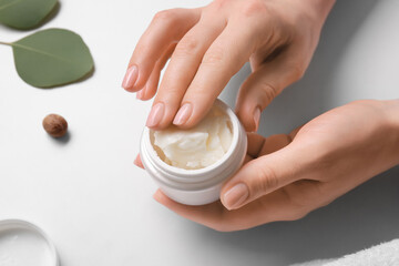 Woman holding jar of shea butter on white background, closeup