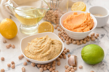 Bowls with tasty hummus on light background, closeup