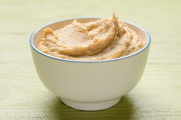 Bowl with tasty hummus on color wooden background, closeup