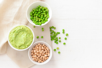 Bowls with tasty green pea hummus and chickpeas on light wooden background