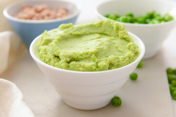Bowl with tasty green pea hummus on table, closeup