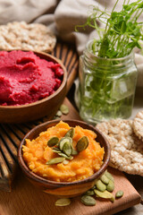 Bowls with tasty hummus on table, closeup