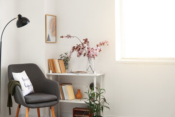 Book shelf with blossoming branches in interior of room © Pixel-Shot