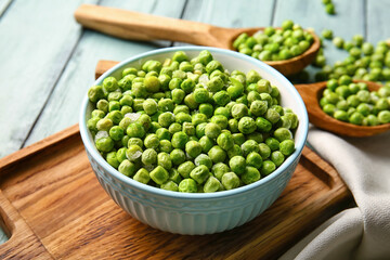 Bowl with frozen green peas on color wooden background