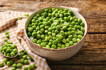 Bowl with frozen green peas on wooden background