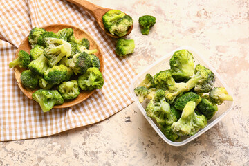Container with frozen broccoli on light background