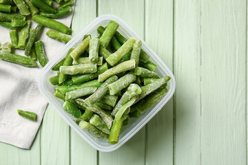 Container with frozen green beans on color wooden background