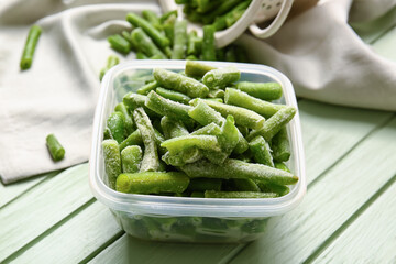 Container with frozen green beans on color wooden background