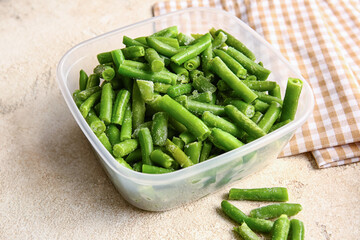 Container with frozen green beans on light background