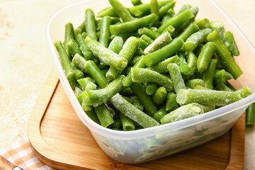 Container with frozen green beans on light background