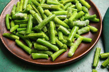 Plate with frozen green beans on color background