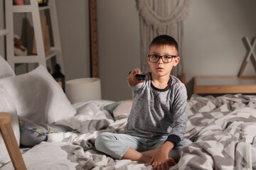 Fototapeta premium Cute boy watching cartoons in bedroom at night