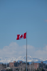 Canada flag flying in the wind with mountains in distance