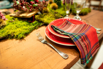 Beautifully prepared table for Christmas with red dishes and tree branches