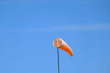 orange wind sock flying in the wind to show wind direction