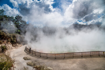 Woman photographing geysers in Waiotapu, New Zealand.