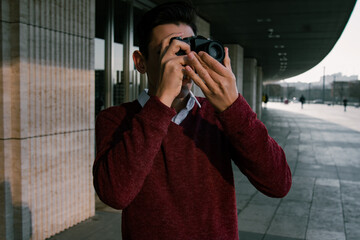 A young and handsome guy with a camera. A tourist filming his surroundings on film. Travel within the country.