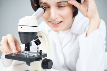 a scientist in a white coat looking through a microscope close-up laboratory