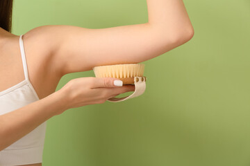 Beautiful young woman with massage brush on color background