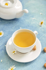 Cup with tasty floral tea and teapot on color background