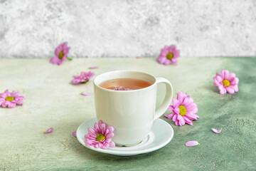Cup of floral tea with flowers on color background