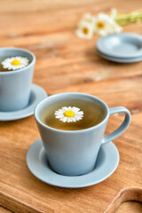 Cups of floral tea on wooden background