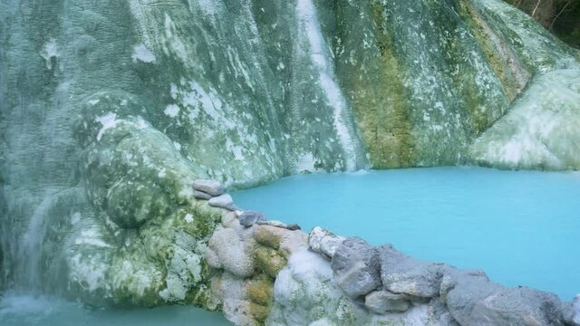 Geothermal pool and hot spring in Tuscany, Italy. Bagni San Filippo natural thermal waterfall in the morning with no people. The White Whale amidst forest.