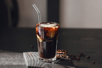 Glass of tasty iced coffee on dark wooden table