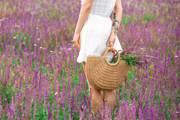 Beautiful young woman with flowers in bag on summer day