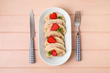 Plate with tasty strawberry dumplings on color wooden background