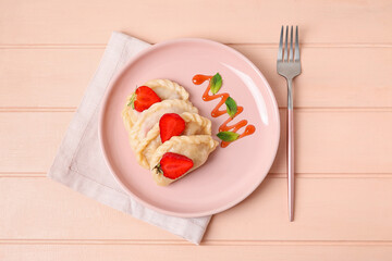 Plate with tasty strawberry dumplings on color wooden background