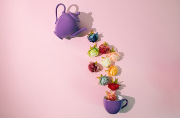 Romantic arrangement made of flower,purple teapot and mug. Rosses in different colors on pastel pink background. flat lay with copy space.