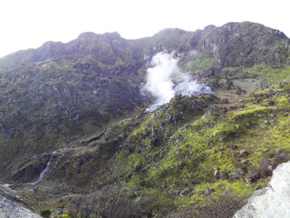Sulfur smoke blows from between the rocks in the crater of the mountain