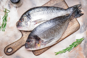 Board with raw dorado fishes on light background