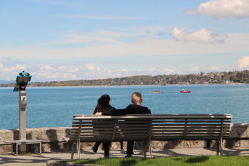 Naklejka na ściany i meble couple sitting on bench in front of the lake