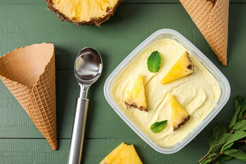 Container with tasty pineapple ice cream on color wooden background