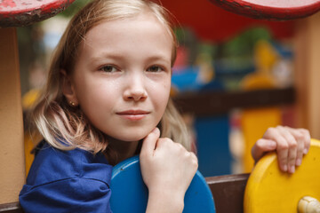 Close up of a lovely young girl looking to the camera thoughtfully while on playground outdoors