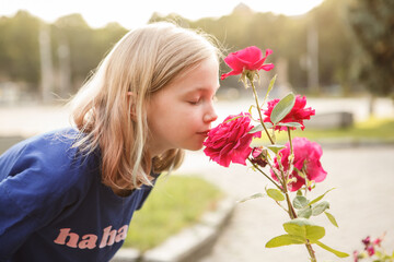 Profile shot of a young lovely girl smelling flowers in the summer