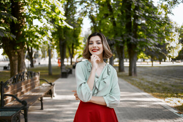 Fototapeta premium pretty woman in red skirt in the park walk lifestyle fresh air