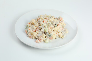 Traditional russian salad Olivier from boiled vegetables and meat with sauce in bowl. Russian New Year or Christmas isolated on white