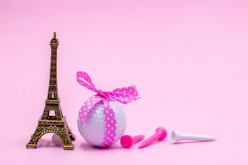Fototapeta na wymiar Golf ball with pink ribbon and Eiffel towel is on pink background