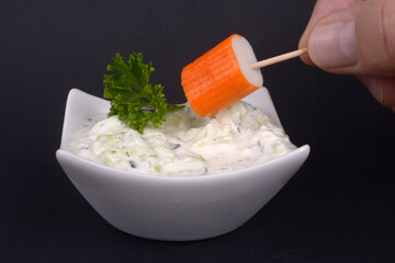 Manger un bâtonnets de surimi avec un pic en bois et de la sauce béarnaise en gros plan sur fond noir © Richard Villalon