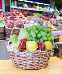 Wicker basket full of different fruits and berries stands on the counter in the store
