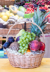 Wicker basket full of different fruits and berries stands on the counter in the store