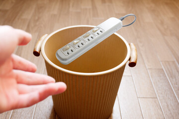 古い電源タップをゴミ箱へ投げ捨てる
