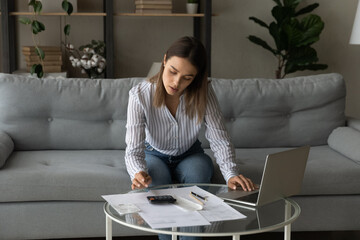 Female individual entrepreneur sit on sofa makes financial report, use calculator calculates...