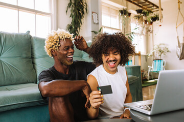 Cheerful young gay couple shopping online at home